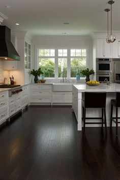 a large kitchen with white cabinets and dark wood floors