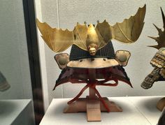 an elaborately designed helmet on display in a glass case with other items around it