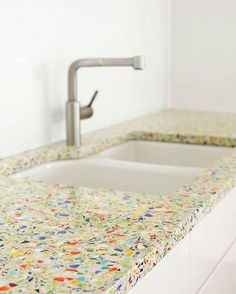 a white sink sitting under a faucet next to a counter top with flowers on it