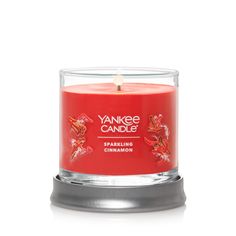 the yankee candle is red and has an orange flower on it's front end