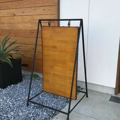 a wooden sign sitting on top of a gravel covered ground next to a planter