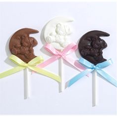 three lollipops with chocolate on them are decorated to look like the moon and bear