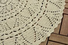 a white crocheted doily sitting on top of a wooden floor