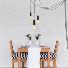 a dining room table and chairs with black and white pillows