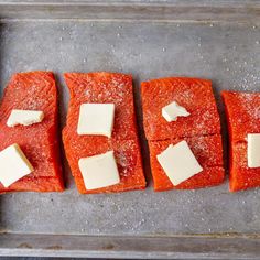 four pieces of salmon with cheese on them sitting on a baking sheet, ready to go into the oven