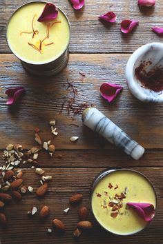 two bowls filled with different types of food on top of a wooden table next to nuts