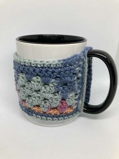 a crocheted coffee mug cozys up with a black handle