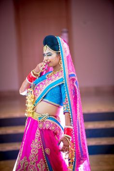 a woman in a pink and blue bridal outfit is talking on her cell phone