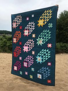 a blue quilt with stars on it sitting in the sand