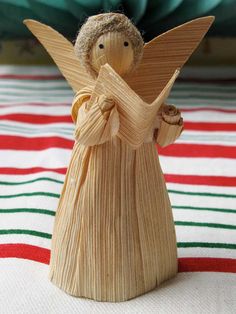 a wooden angel figurine sitting on top of a striped cloth covered tablecloth