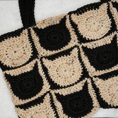 a crocheted black and white bag sitting on top of a blanket