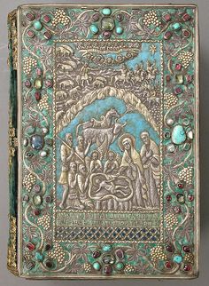 an intricately decorated book with gold trimming and beads on the cover, depicting people surrounded by animals