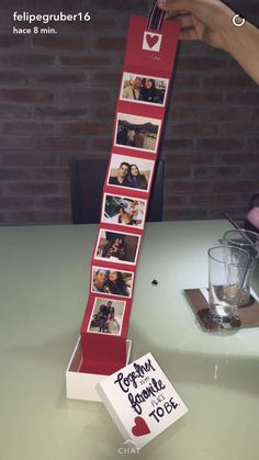 a person holding up a red ribbon with photos on it and a card attached to it