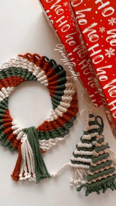 two christmas wreaths are sitting next to a red box with a white and green ribbon