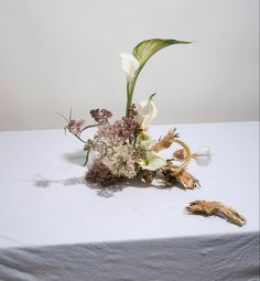 an arrangement of flowers on a white table cloth