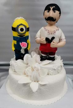 two small figurines sitting on top of a wedding cake