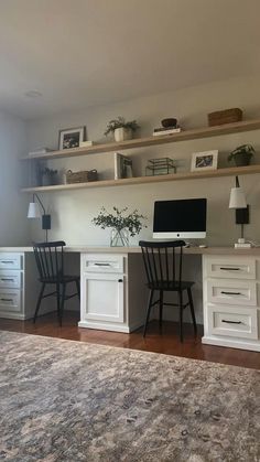 a desk with two chairs and a computer on top of it in front of a window