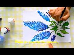 someone is painting blue flowers on white paper