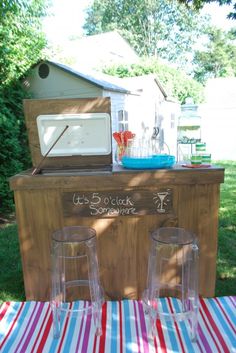 two glasses sitting on top of a table next to an ice chest and cooler in the back yard