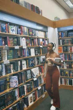 a woman standing in front of a bookshelf with headphones on her ears