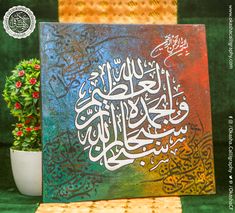 a painting with arabic writing on it next to a potted plant