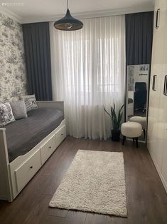 a bed room with a neatly made bed next to a window and a rug on the floor