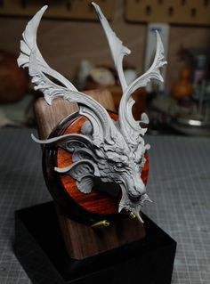 a sculpture of a dragon head on top of a wooden stand