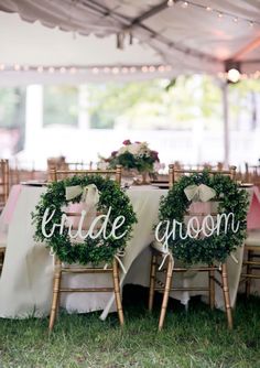 two chairs with wreaths on them are set up for a wedding reception under a tent