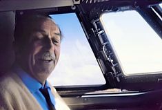 an older man wearing a suit and tie sitting in the back seat of a car