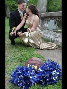 a man kneeling down next to a woman in a dress and holding a basketball on the ground