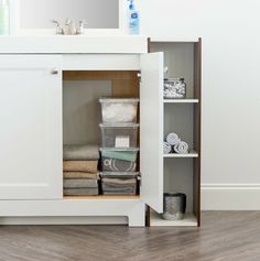 a white bathroom cabinet with towels and other items in front of the mirror on the wall