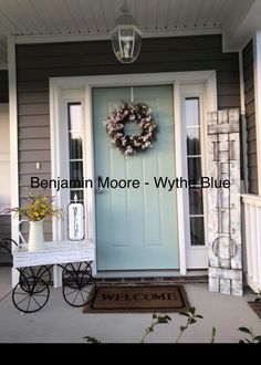 a blue front door with a wreath on it and a welcome mat in front of it