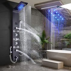 the shower head is open with water coming from it and there are plants in the background