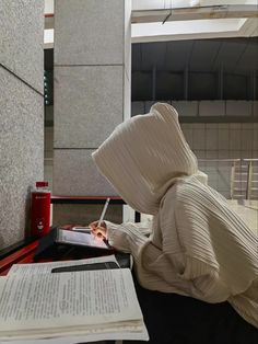 a person in a white outfit writing on a piece of paper