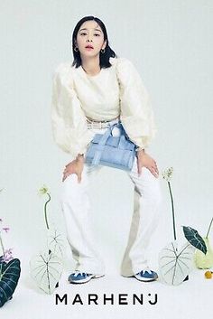 a woman sitting on top of a white chair next to flowers and plants in front of her