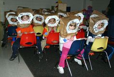 several children sitting in chairs with paper bags on their heads