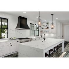 a large kitchen with white cabinets and marble counter tops