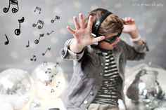 a young boy wearing headphones and holding his hands up in front of mirrored balls