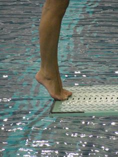 a person standing on top of a swimming pool with their feet in the water,