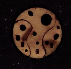 a wooden clock with black dots on it's face in the dark night sky