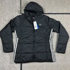 Womens Adidas B10317 Black Originals Puffer Jacket Size M Slim Jacket. Inside Chest Pockets. Hood With Elastic Binding. Full Two-Way Zip With High Collar. 100% Recycled Polyester Plain Weave. Lined. 3-Stripes Jacket. Fleece-Lined Pockets With Zip. Black Puffer Jacket For Spring Outdoor, Adidas Outerwear For Winter Outdoor Activities, Adidas Winter Outerwear For Cold Weather, Adidas Outerwear For Cold Weather, Adidas Outerwear For Outdoor Winter Activities, Adidas Outdoor Outerwear For Spring, Spring Adidas Outdoor Outerwear, Adidas Spring Outdoor Outerwear, Adidas Sporty Cold Weather Outerwear