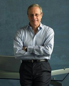 a man standing with his arms crossed in front of a wall