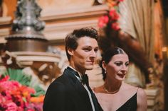 a man and woman standing next to each other in front of a flower display at a formal event