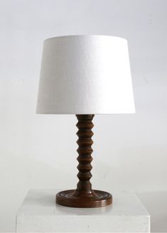 a wooden lamp with a white shade on the top and bottom of it's base