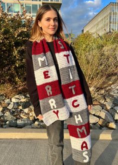 a woman wearing a red and white crocheted scarf with the words merry on it