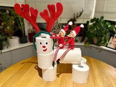 two elfs are sitting on top of toilet paper rolls and one is holding a snowman