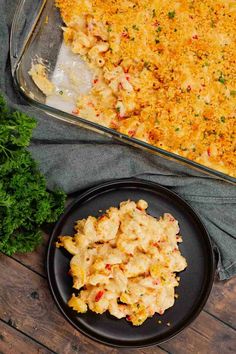 a casserole dish with chicken and cheese on a black plate next to parsley