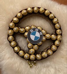 a bmw emblem on a brown belt with white and gold beads around it, sitting on a furry surface