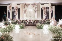 an elaborately decorated wedding stage with flowers and fairy lights on the floor, surrounded by greenery