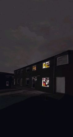 an empty street at night with the lights on and buildings lit up in the dark